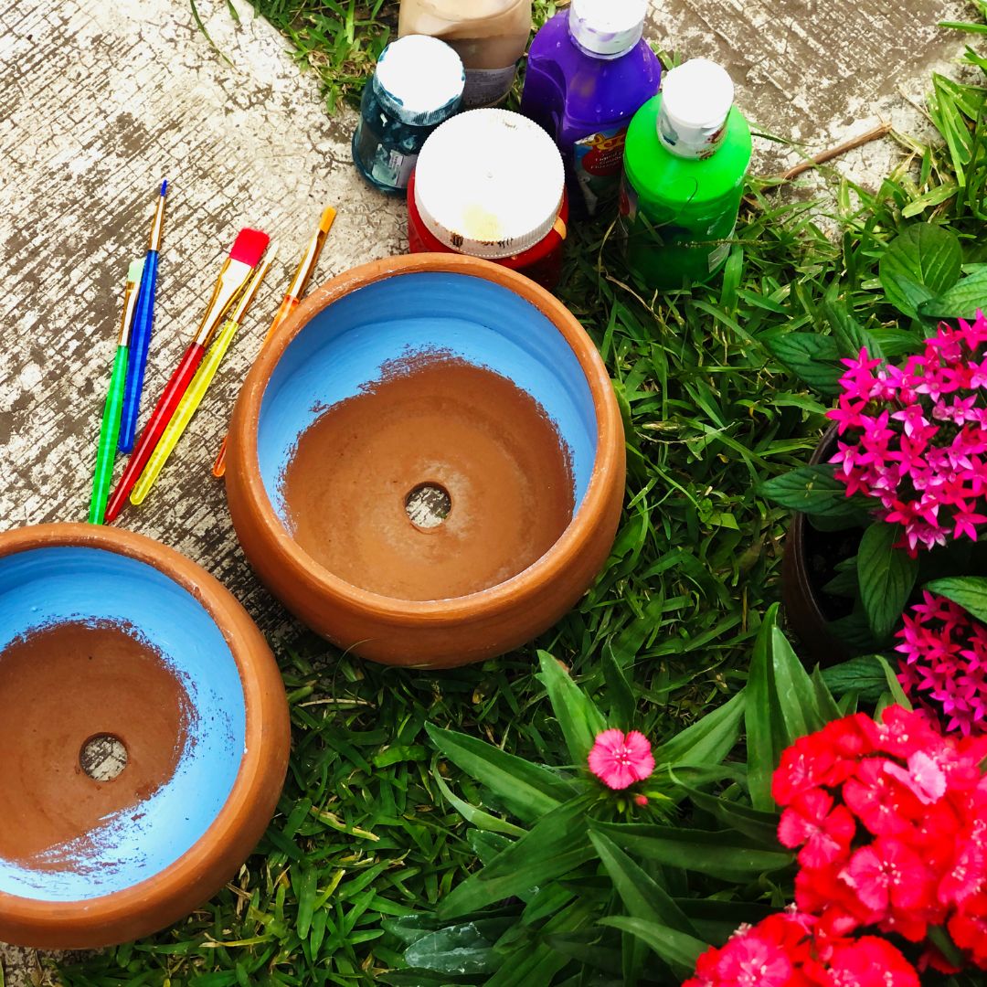 Painted pots on ground by flowers