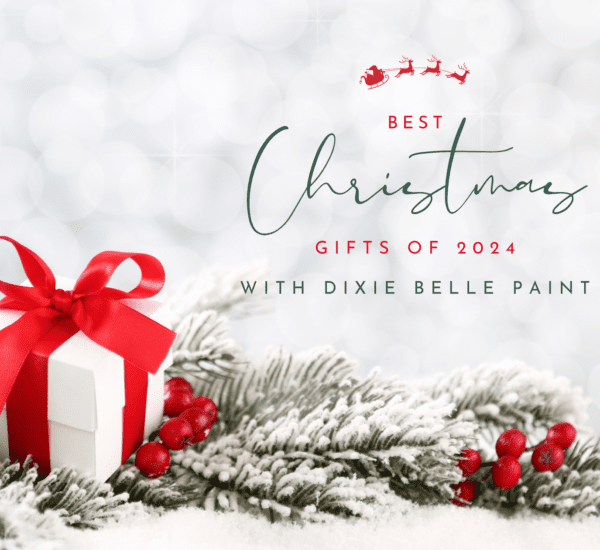 a white present with red ribbon, red berries and green pine needles sitting on a table top, the words Best Christmas Gifts of 2024 with Dixie Belle Paint is printed above the gift in front of a white sparkly background