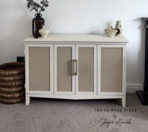 A photo of a cabinet painted with Drop Cloth Chalk Mineral Paint sitting on a brown carpeted floor, in front of a white wall