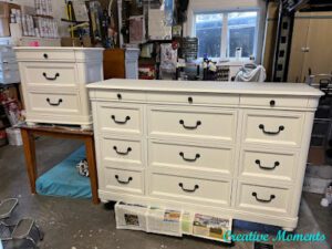 A white painted nightstand and a white painted dresser with the hardware applied 